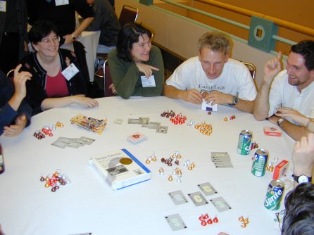 four people sitting at a round table with cards and candy