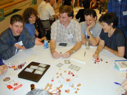 five people sitting at a round table with cards and candy