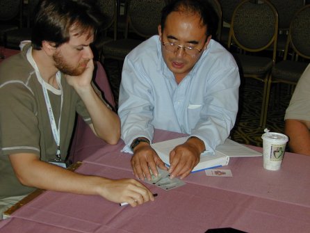 two people looking at a book and their hand of cards