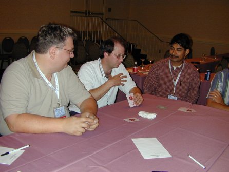 a person with a hand of cards talking to two people on each side