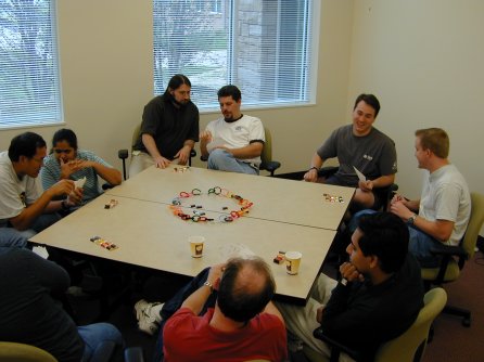 Pairs of people, looking at their hand of cards, around a table