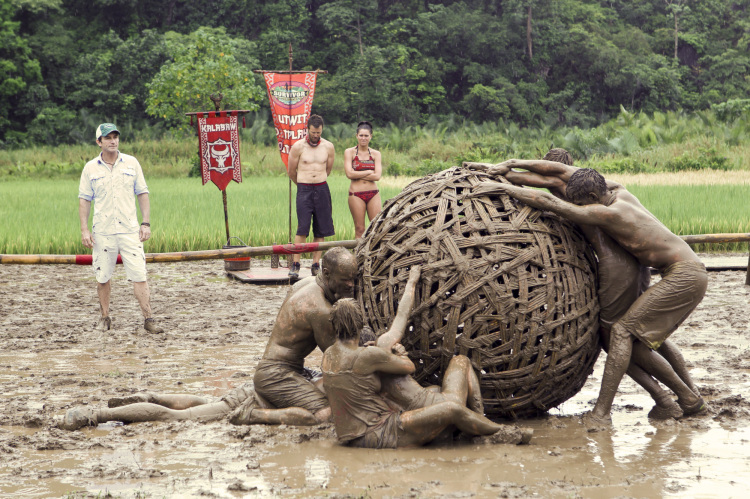 people wrestling with a ball in the mud