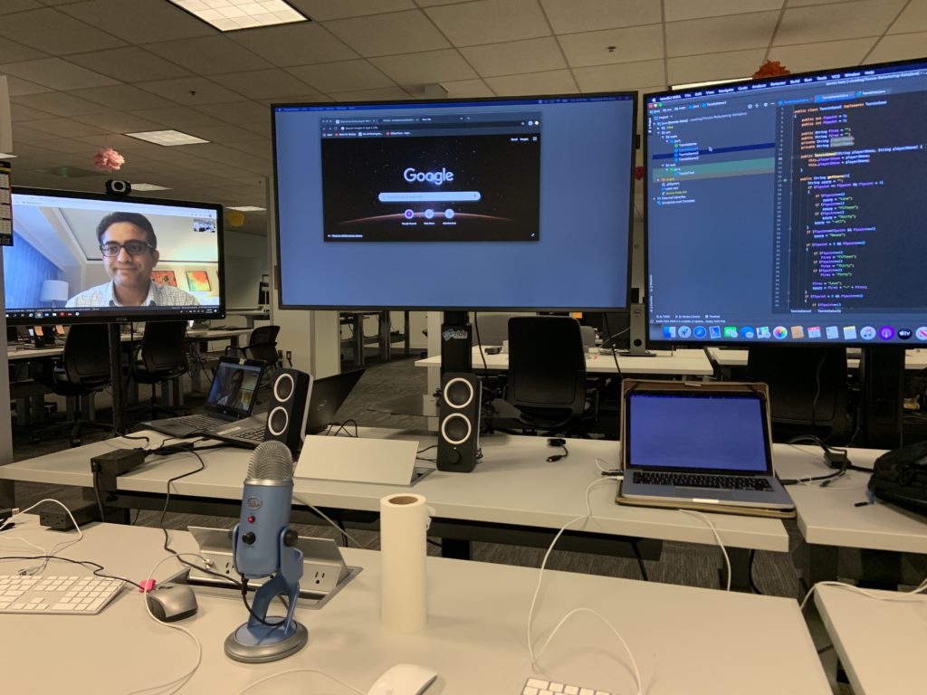 desk with three monitors, microphone, speakers, and laptop