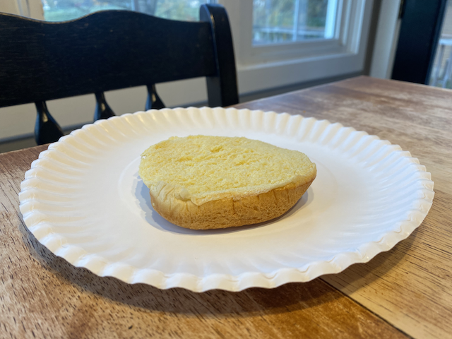 A plain hamburger bun bottom on a paper plate