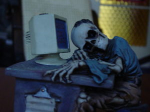 Too. Much. Time. Clothed skeleton resting head on desk in front of a computer